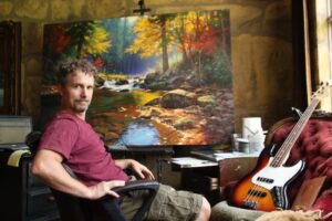 Mark Keathley in front on his easel with a mostly complete painting