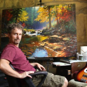 Mark Keathley sits in front of an easel at his studio