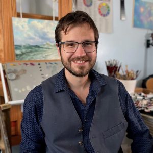 Abraham smiling in front of an easel in his studip